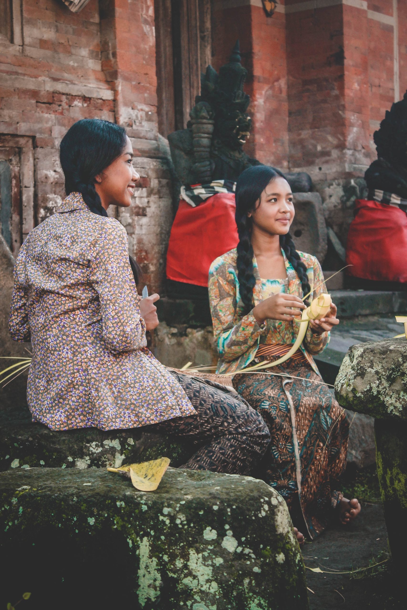 Two girls who are making “Tipat” is a dish of rice wrapped in “Busung” or in English young coconut leaves